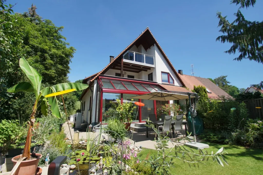 Wintergarten Ahorntal von der Gartenseite mit Terrasse und Sonnenschirm