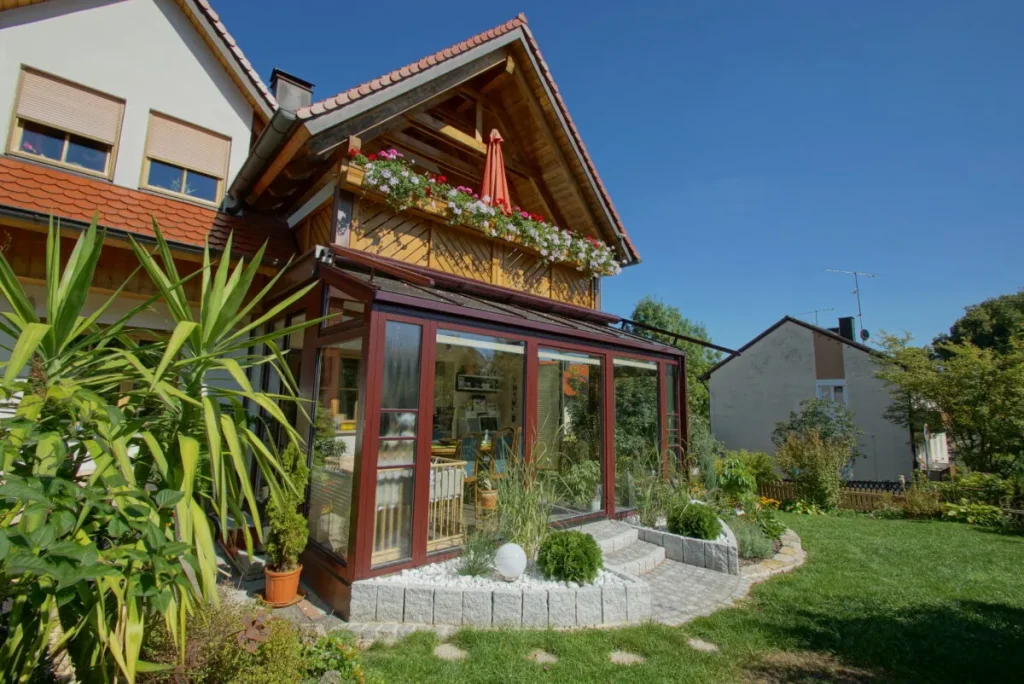 Wintergarten in Heiligenstadt mit rotbraunen Rahmen unter dem Holzbalkon