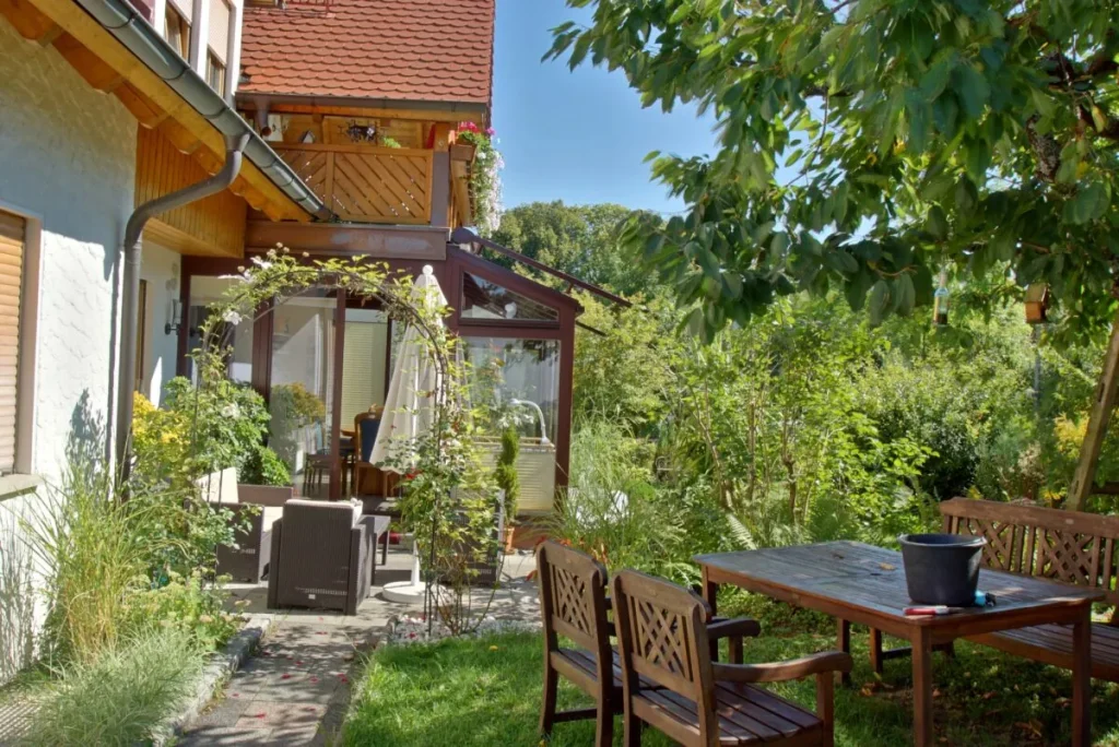 Terrasse mit Gartentisch neben dem Wintergarten in Heiligenstadt, der aus der früheren Terrasse unter dem Balkon entstand