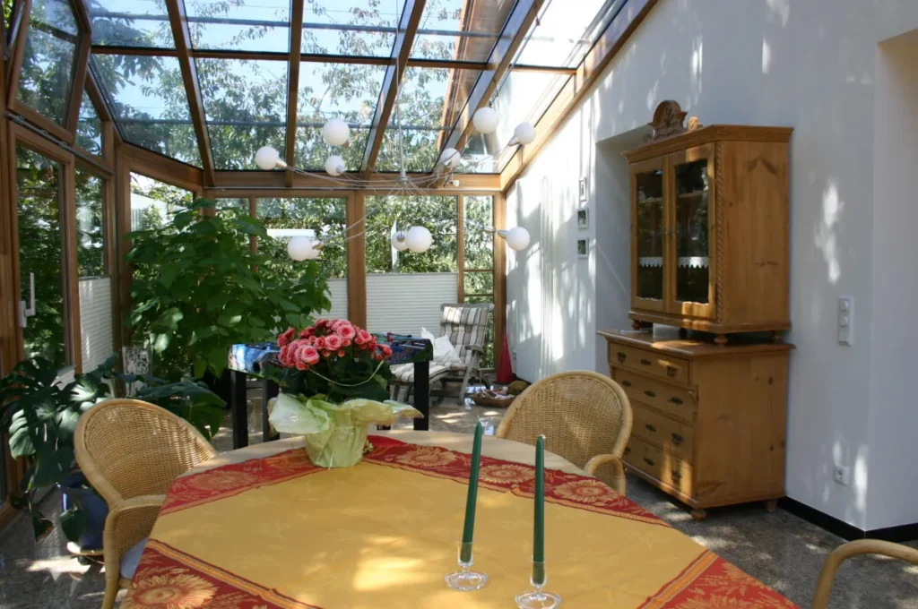 Wintergarten in Kunreuth von innen: Holzkonstruktion, Esstisch und Pflanzen unter dem Glasdach